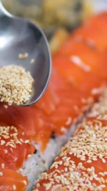 Suşi siyah arka planda dönüyor, beyaz tabakta, yakın plan. Suşi seti. Dikey video. Asya yemekleri. Yüksek kalite 4k görüntü