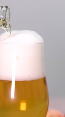 Büyük bir bardak altın soğuk bira yakın plan. Bira köpüğü yavaşça camdan aşağı akar. Karbonatlı içecek kabarcıkları. Bira köpüğü yavaşça camdan aşağı akar. Karbonatlı içecek kabarcıkları. Yüksek kalite 4k 