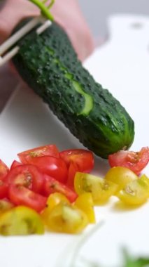 yeşil salatalıklar mutfakta bıçakla kesilir. Sağlıklı sebze salatası konsepti. Mutfaktaki yeşil salatalıklar yakın plan yaşam tarzını dilimlere ayırıyor. Salatalık kabuğu soymak.