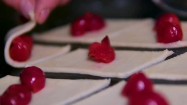 Bir kadın kiraz ya da kiraz dilimlenmiş hamurla sarılır. Ev mutfağında çörekler ve hamur işleri, ağır çekimde. Kirazlı kruvasan yapma süreci