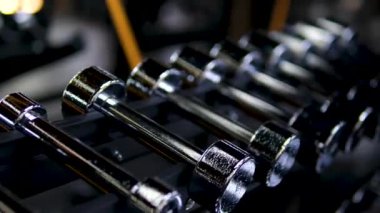 Kapalı spor salonunun arka planında parlak metalik halterler var. Yüksek kalite 4k görüntü