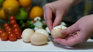 Haşlanmış yumurtayı nazikçe soyan bir kadının elleri besleyici bir atıştırmalık hazırlamanın basit ve tatmin edici sürecini gözler önüne seriyor. Yüksek kalite 4k görüntü