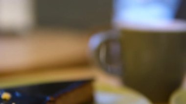 Kahve fincanda sütlü kahve ve kahve masasında tatlı. Sabahları kahvecide sütlü kahveyle tatlı yiyor, yakın plan. Kahve molası. Yüksek kalite 4k görüntü