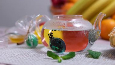 İçi organik bitkisel karışım dolu cam çaydanlık sakinleştirici sağlık faydaları getirir. Doğal malzemeler ılık bira içinde yüzer, huzurlu ve sağlıklı yaşam tarzı için rahatlatıcı bir ritüel yaratır..