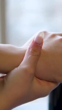 Kimliği belirsiz bir kadının avucuna krem sürerken ve koyu kahverengi arka planda el derisine sürerken yakın plan fotoğrafı.