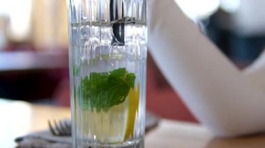 Buz küplerinin üzerine su dökmek, limon dilimleri ve naneli limonata yapmak. Yüksek kalite 4k görüntü