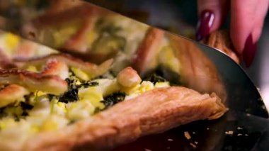 Becerikli ev yemekleri dikkatlice kesiyor ve taze fırınlanmış ıspanak ve pazılı turtayı kırsal mutfak masasında servis ediyor. Yüksek kalite 4k görüntü