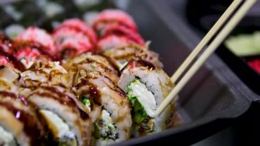 Bambu çubukları tutuyor ve somonla taze suşi topluyor. Yüksek kalite 4k görüntü