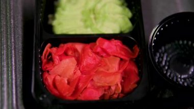 Dişi bir el beyaz bir tabaktan suşi çubuğu alır. Sushi, wasabi ve turşulu zencefil beyaz bir tabakta. Yüksek kalite 4k görüntü