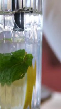 Buz küplerinin üzerine su dökmek, limon dilimleri ve naneli limonata yapmak. Yüksek kalite 4k görüntü