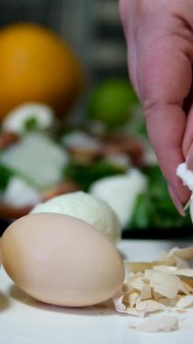 Eller, Mutfak Lavabosunda Bir Kase Su Üzerine Kaynamış Yumurta Dikkatlice Soyar, Ev Mutfağı Ayarlarında Taze İçindekilerle Basit Bir Pişirme Sürecini Gösterir. Yüksek kalite 4k