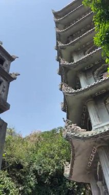 Bereketli yeşil tepeler ve uzaktaki kırsal manzarayla çevrili kayalık bir uçuruma tünemiş pagoda 'nın çarpıcı hava görüntüleri. Huzurlu sahne, doğal güzellikle kültürel mirası harmanlıyor..