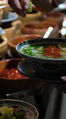 Sıcak bir kase Vietnam usulü tavuk çorbası, limonlu ve taze otlu. Bir kase çorbaya limon sıkıştır.