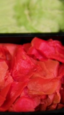 Dişi bir el beyaz bir tabaktan suşi çubuğu alır. Sushi, wasabi ve turşulu zencefil beyaz bir tabakta. Yüksek kalite 4k görüntü