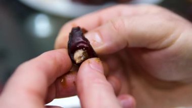 Beyaz arka plana düşen meyvelerin yavaş çekimde çekilmesi. Eller meyveden çukuru çıkarsın.