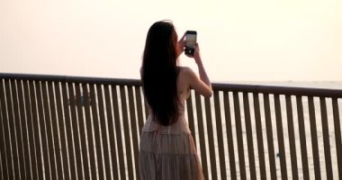 Güzel bir kız akıllı telefonuyla dikey bir fotoğraf çekiyor. Kadın sosyal medya için fotoğraf çekiyor. Dişi Asya dağlarında seyahat eder, kalderada. - Evet. Yüksek kaliteli FullHD görüntüler