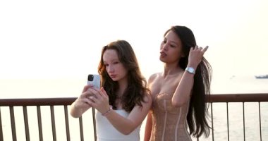 İki Asyalı Avrupalı kız selfie çekiyor. Kadınlar, arkadaşlar ve özçekim sahilde tatil ya da sosyal medya, bağlantı ya da eğlence için. Kadın kişi, dijital cihaz ve bağlanmak için birlikte mutlular.,
