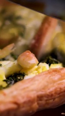 Becerikli ev yemekleri dikkatlice kesiyor ve taze fırınlanmış ıspanak ve pazılı turtayı kırsal mutfak masasında servis ediyor. Yüksek kalite 4k görüntü