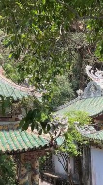 Bereketli yeşil tepeler ve uzaktaki kırsal manzarayla çevrili kayalık bir uçuruma tünemiş pagoda 'nın çarpıcı hava görüntüleri. Huzurlu manzara, Da Nang Vietnam 'ın doğal güzelliğini harmanlıyor. 04.12.2025