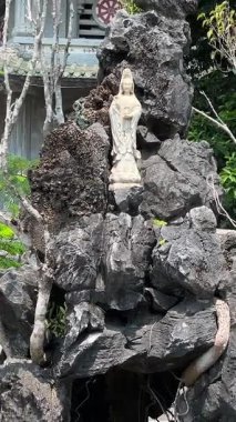 Bereketli yeşil tepeler ve uzaktaki kırsal manzarayla çevrili kayalık bir uçuruma tünemiş pagoda 'nın çarpıcı hava görüntüleri. Huzurlu sahne, doğal güzellikle kültürel mirası harmanlıyor..