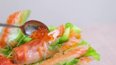 Kırmızı havyar kaşıkta, balık yumurtası cam kavanozda. Somon balığı yumurtası havyarı servis masasında. Lezzetli. Bana taze havyar sarması için biraz havyar vermelisin. Arkaplan. Deniz ürünleri. Yavaş çekim.