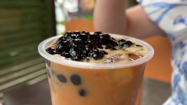 Kadın buzlu sütlü çay içiyor. Kahveye topioca ekle