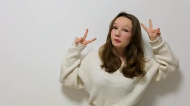 Gülümseyen ve zafer işareti gösteren genç bir kadın izole edilmiş arka planda neşeli bir yüzle. Yeşil ekran krom anahtarı. Yüksek kalite 4k görüntü