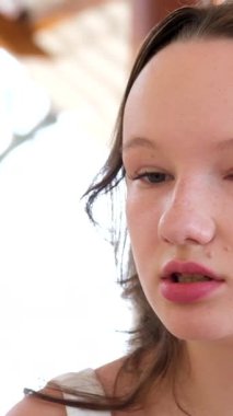 Güneşli şehir arka planında saçlarını tarayan ve kameraya gülümseyen neşeli sarışın kadın öğrenci portresi. Yüksek kaliteli FullHD görüntüler