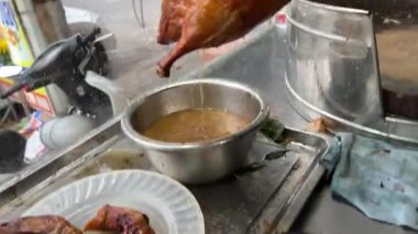 Kahverengi bir kesme tahtasının üzerinde gümüş bir bıçakla kızarmış ördek doğrayan biri. Yüksek kalite 4k görüntü