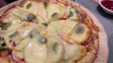 Salamlı, zeytinli ve peynirli iki yuvarlak pizza ve yanında iki soslu gri bir masa ve dokusu daha yakın. Yüksek kalite 4k görüntü