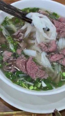 Vietnam Pho Çorbası Geleneksel Vietnam pho çorbası biftek dilimleri, erişte ve bir kasede taze otlar, Vietnam mutfağı konsepti. Yüksek kalite 4k görüntü