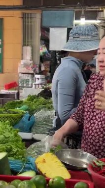 Mutlu çiftçi babası ve genç kızı çiftçi pazarındaki kadın alıcıya taze sebzelerle birlikte eko kağıt torba veriyorlar. Vietnam Danang 04.25.2025