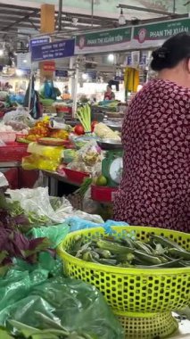  Yerel marketten domates alan kadın sebze kabuğu ananas satıyor. Vietnam Danang 04.25.2025