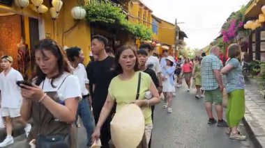 Turistler akşam kentinde dolanıp farklı milletlerden güzel sarı binalara bakıyorlar. Vietnam 'ın tarihi Hoi An şehrine gidiyorlar. 05.02.2025