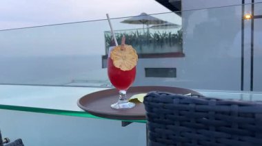 Kırmızı kokteylli plastik bardak ve yüzme havuzunun kenarında çizgili kamış. Yaz tatili havası, güneşli hava, ferahlatıcı su içeceği. Rahatlatıcı tropikal otel atmosferi, tatil