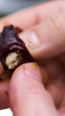 Beyaz arka plana düşen meyvelerin yavaş çekimde çekilmesi. Eller meyveden çukuru çıkarsın.