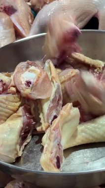 Süpermarketlerdeki işçilerin elleri, metal eldivenler giyerken çiğ tavuk parçaları koyarken yakın çekim çekimleri. Yüksek kalite 4k görüntü