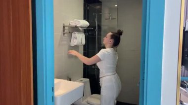 Kız lavabo banyosunda elini yıkıyor ve aynaya bak. Ellerini banyoda havluyla kurula. Yüksek kalite 4k görüntü