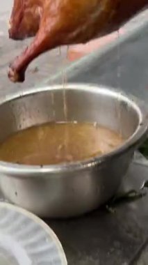 Kahverengi bir kesme tahtasının üzerinde gümüş bir bıçakla kızarmış ördek doğrayan biri. Yüksek kalite 4k görüntü
