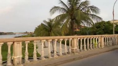 Şehirde motosikletli popüler bir köprüyü çekerken... trafikte palmiye ağaçlarında... sıradan bir hayat... taksi bisikleti Hoi An City Vietnam 05.02.2025...