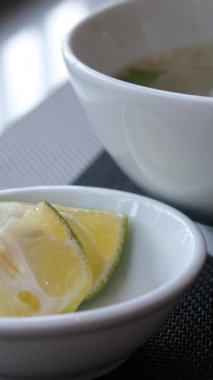 Limonlu çorbaya sıkışan el, Bangkok 'un hareketli restoranlarında bir kase Po' nun üzerine limon sıkıyor ve bulaşık tadını arttırıyor. Yüksek kalite 4k görüntü