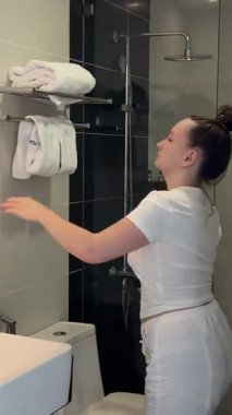 Kız lavabo banyosunda elini yıkıyor ve aynaya bak. Ellerini banyoda havluyla kurula. Yüksek kalite 4k görüntü