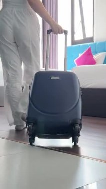 Otele bavulla girer. Seyahat çantasıyla geçen kendine güvenen beyaz bir kadınla otel odası. Güzel bayan turist yaz tatillerini tatil köyüne girerek geçiriyor. Turizm ve seyahat kavramı.