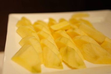 Olgun sarı mango eti, pürüzlü dilimler, beyaz bir tabağa yerleştirilmiş çok renkli bir arka plan. Yüksek kalite fotoğraf