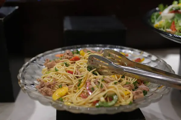 Ev yapımı makarna salatası ve dirsek makarna ve konserve ton balığı, havuç, mor lahana, domates, mısır, yeşil bezelye ve mayonez sosu ahşap masa üzerinde beyaz bir tabakta. Yüksek kalite 