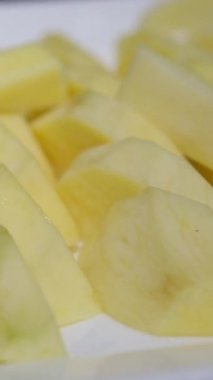 Olgun sarı mango eti, pürüzlü dilimler, beyaz bir tabağa yerleştirilmiş çok renkli bir arka plan. Yüksek kalite fotoğraf