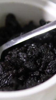 Kuru üzümler yavaşça tahta kase arka planında dönüyor. Kurutulmuş üzümler yakından. Kurutulmuş meyve ve kuru böğürtlen. Yüksek kalite 4k görüntü