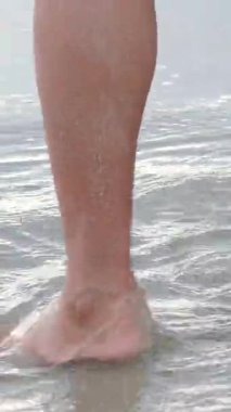 Ayakları çıplak ayakla kumlu okyanus sahillerinde yürüyen turist bacakları gün batımında lüks otellerde ayak izleri bırakıyor. Bir kadın yaz tatilinde dinlenmekten zevk alıyor. Seyahat, turizm, seyahat 