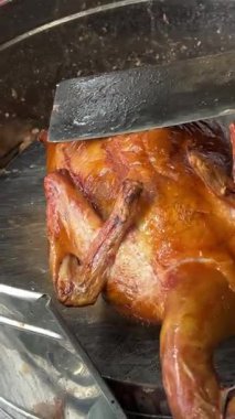 Kahverengi bir kesme tahtasının üzerinde gümüş bir bıçakla kızarmış ördek doğrayan biri. Yüksek kalite 4k görüntü