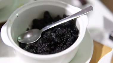 Kuru üzümler yavaşça tahta kase arka planında dönüyor. Kurutulmuş üzümler yakından. Kurutulmuş meyve ve kuru böğürtlen. Yüksek kalite 4k görüntü